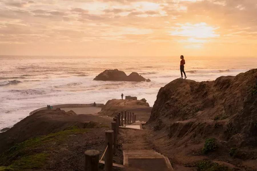 Deux personnes se tiennent debout sur des rochers surplombant l’océan aux Sutro Baths à San Francisco.